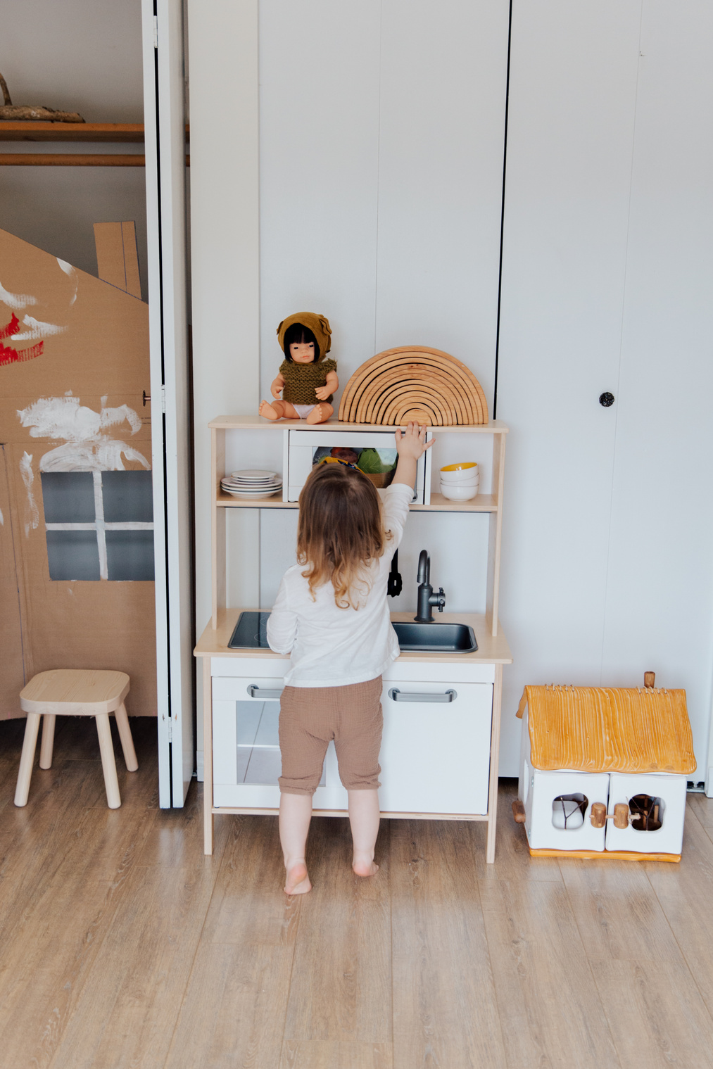Cute toddler girl playing with toy kitchen at home